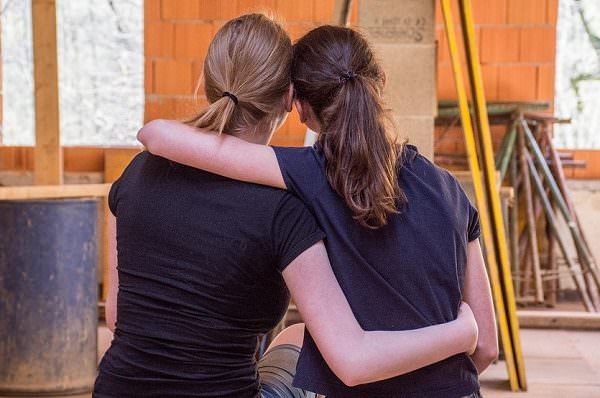 two women sitting on a bench and hugging