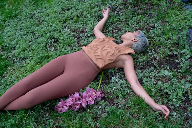 woman lying on the ground wearing an earthen top