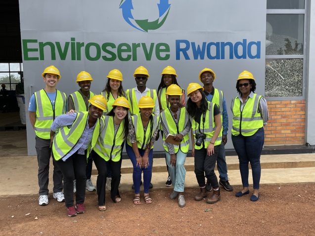 students in hard hats and safety vests in front of enviroserve banner