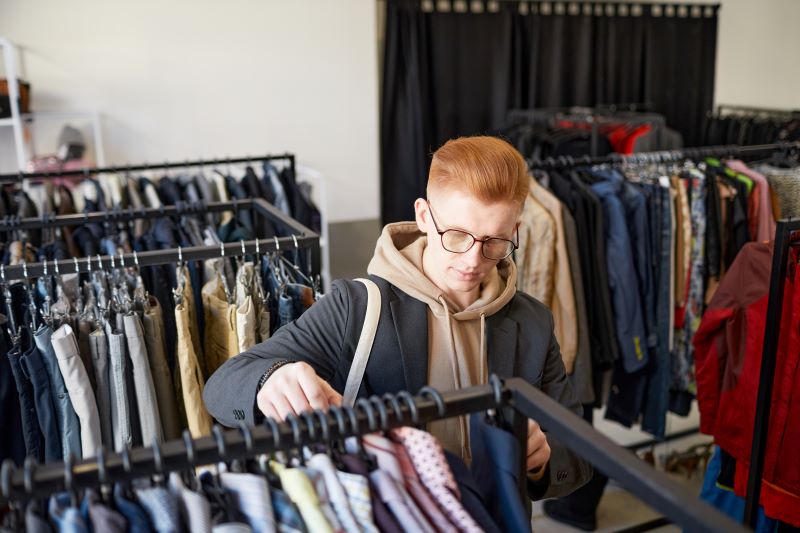 Young man looking at clothing in a thrift shop