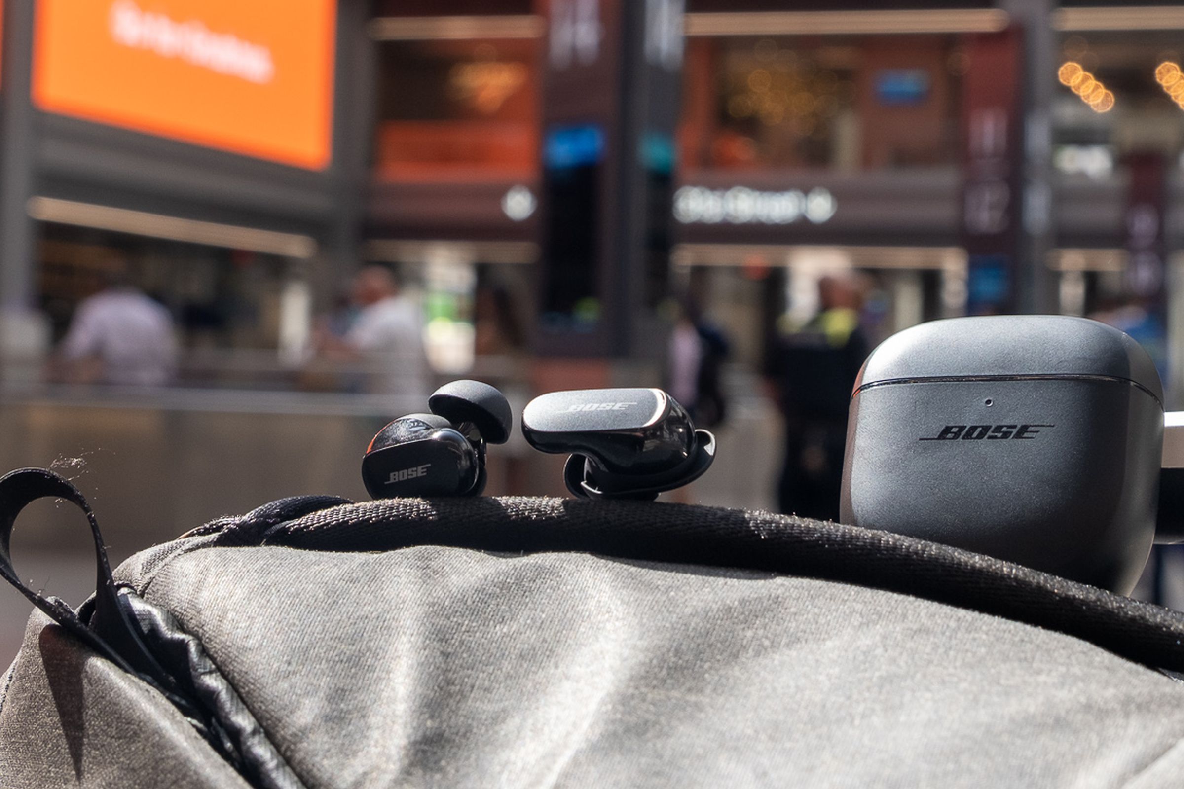 The Bose QC Earbuds II pictured on top of a backpack at Moynihan Train Hall in New York City.