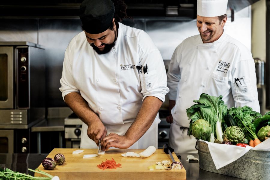 Student cutting vegetables under supervision at the Auguste Escoffier School of Culinary Arts