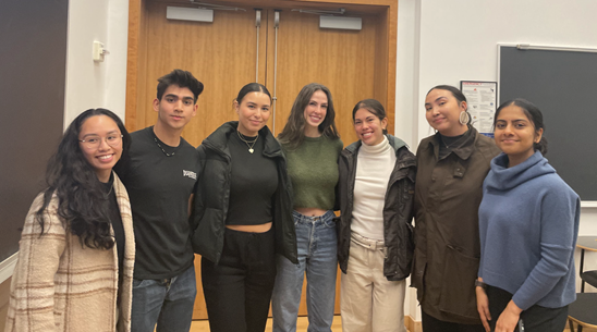Group of students smile in front of double doors