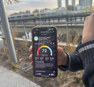 Individual holding a phone showing air quality measurement