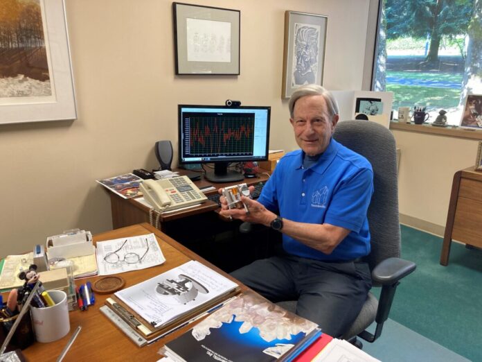 Inventor and philanthropist Jerry Paros, pictured in his office holding a Paroscientific