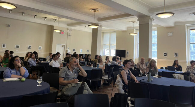 attendees sit at tables in a conference room