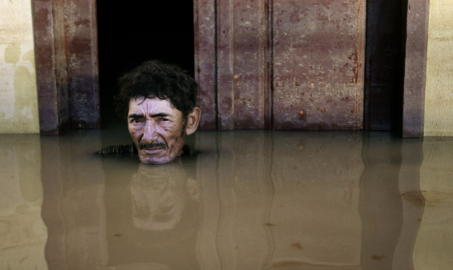 Excerpt from “Deluge” shows a man submerged in floodwaters. Courtesy of Gideon Mendel