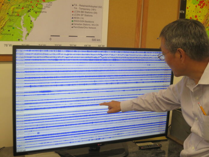 Scientist looking at seismogram on big-screen TV.
